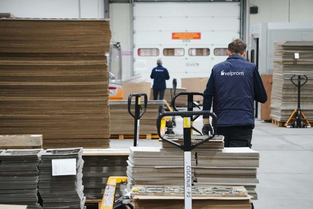 a man in a warehouse moving a cart full of boxes